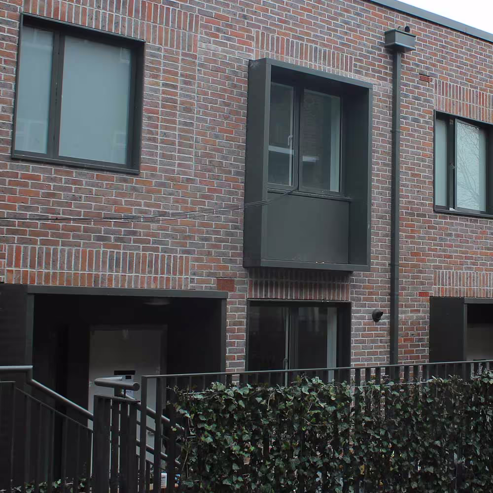 Newly completed residential buildings in a contemporary housing estate with landscaped surroundings.