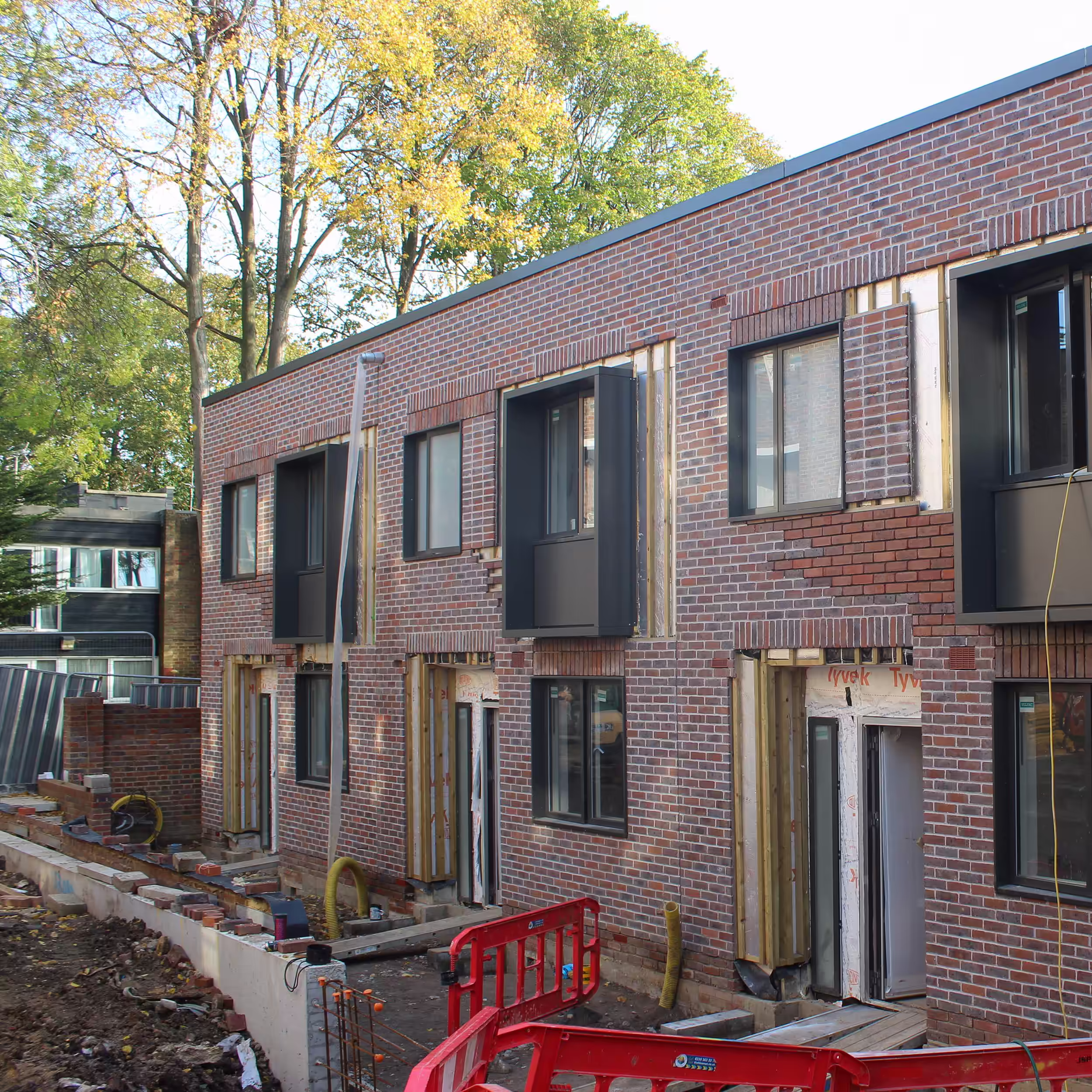 Construction workers installing roofing on a newly built home during final stages of development.
