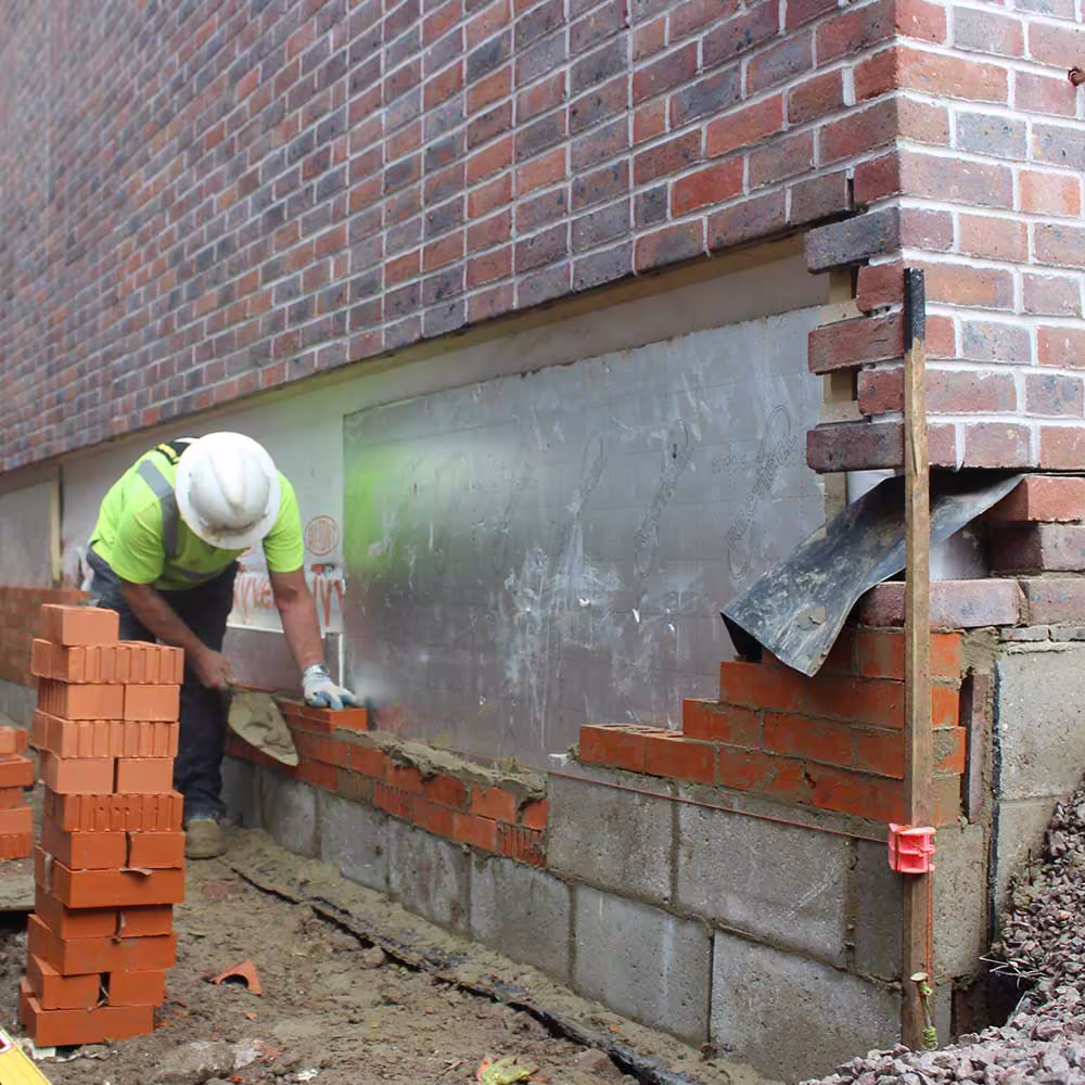 Modern brick and cladding façade of a new residential building under clear daylight.