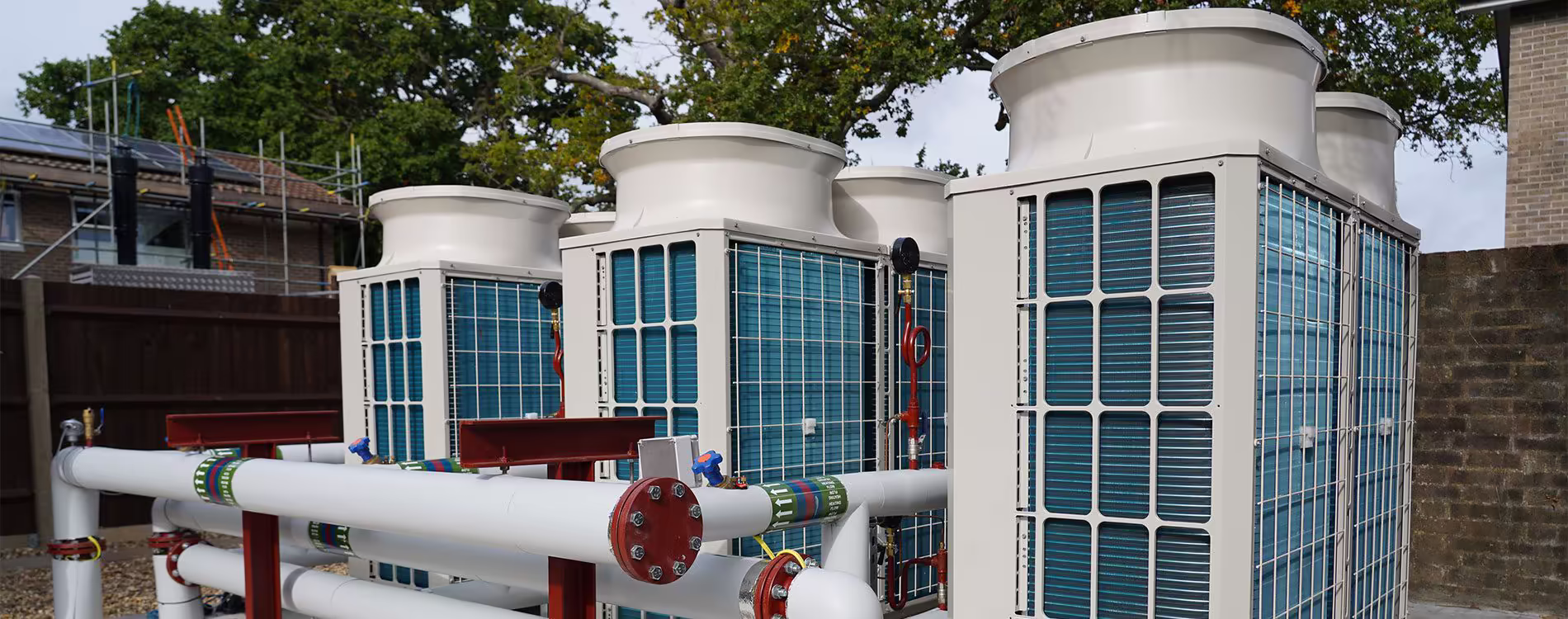 Technician installing a modern air source heat pump unit outside a residential property as part of an energy-efficient heating upgrade.