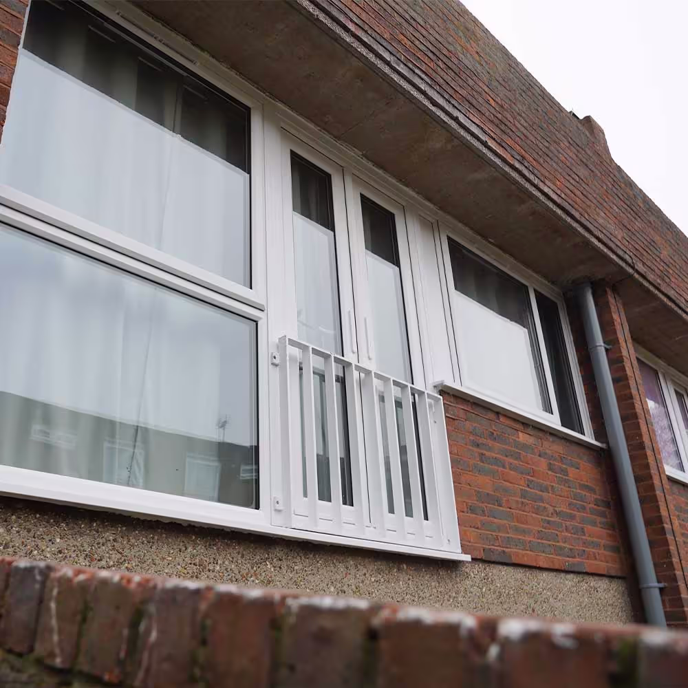 A newly installed white uPVC window and French doors with a matching white Juliet balcony, part of the external upgrades in the planned decorations programme.