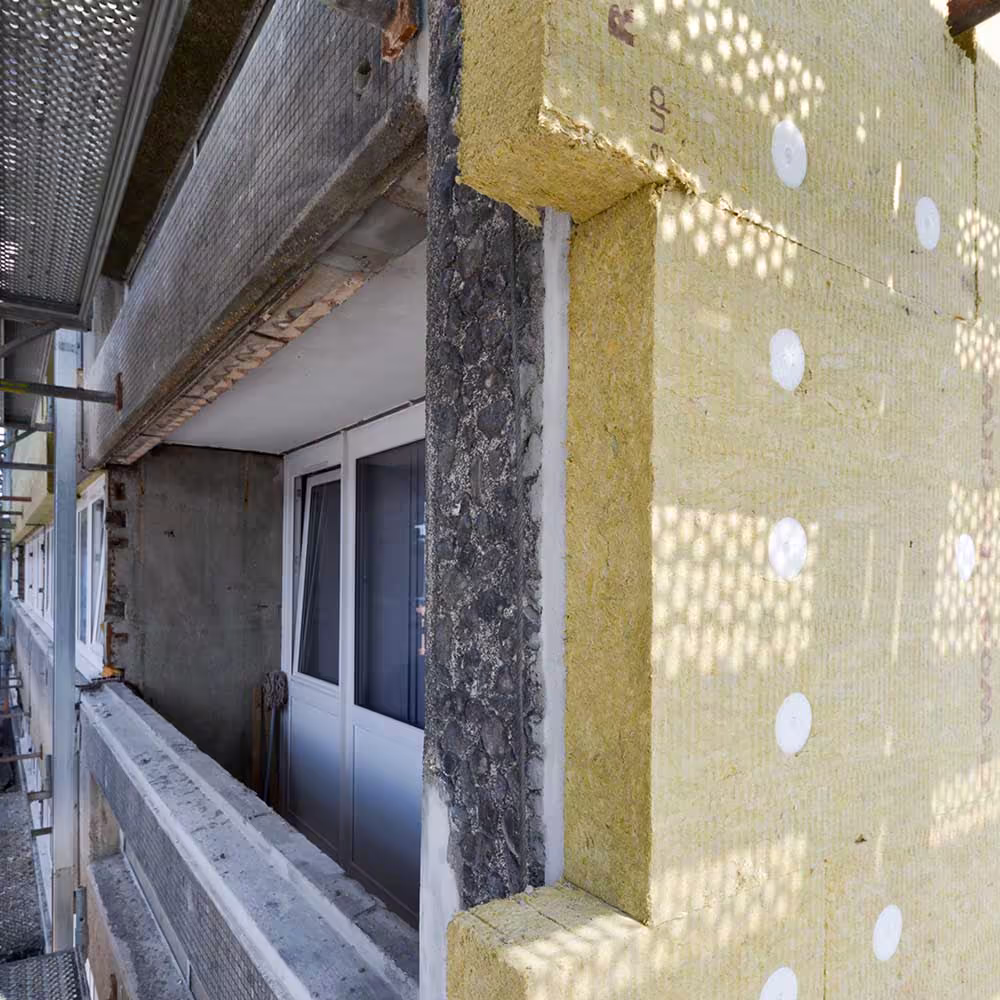 A close-up of the planned improvements on a resident's balcony, showing the new, thick external wall insulation installed on the building's facade.