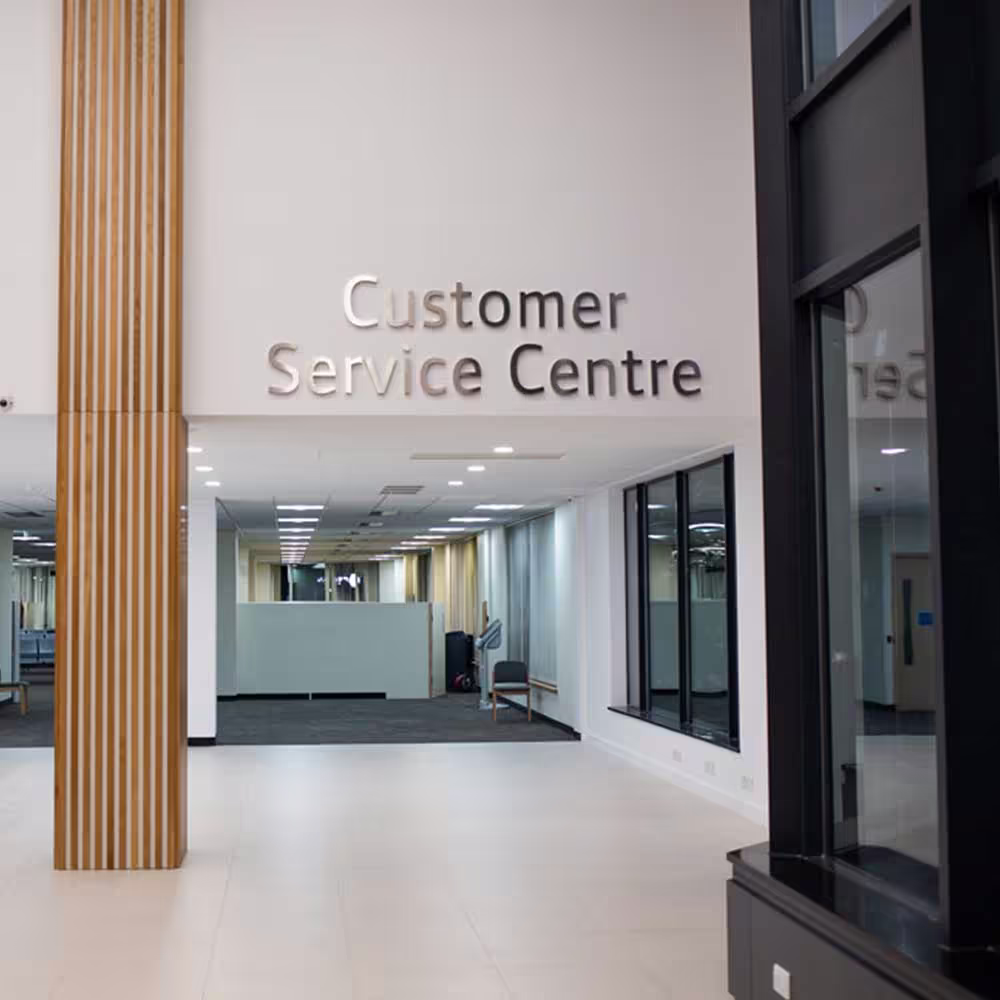 The entrance to the new 'Customer Service Centre' within the refurbished building, showing the clear silver signage on a white wall and a view into the modern open-plan area.