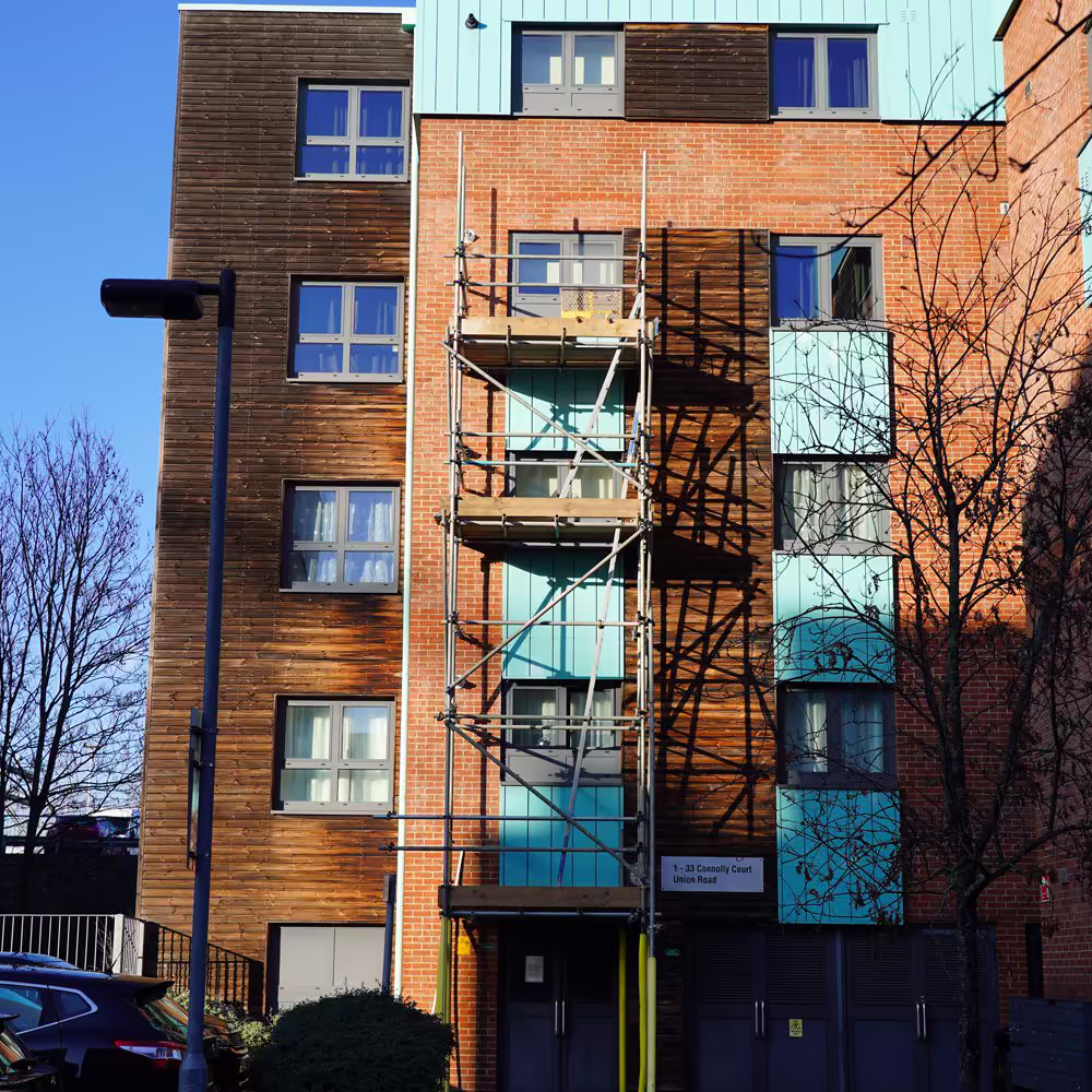 The facade of Connolly Court, an NHS keyworker accommodation block, with a scaffolding tower in place for carrying out targeted external repairs.