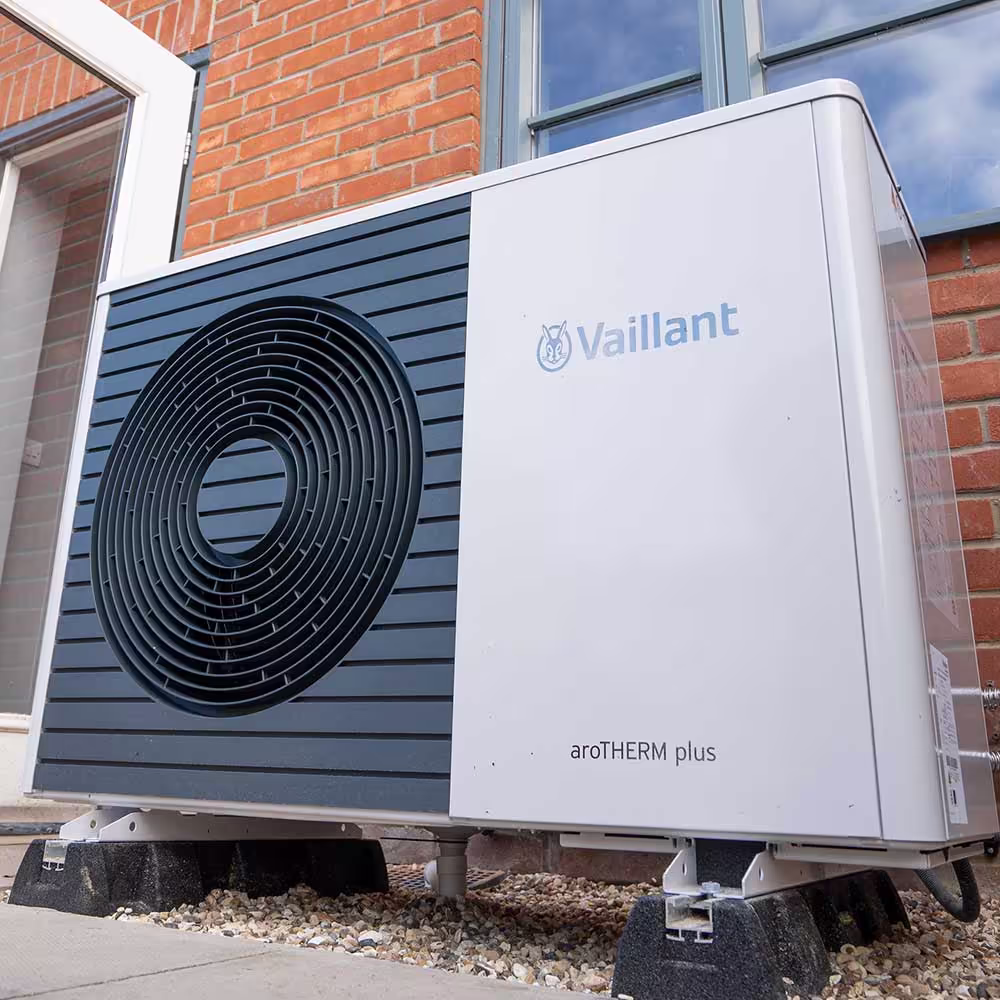 A Vaillant aroTHERM plus Air Source Heat Pump unit installed outside a home on anti-vibration mounting feet, providing an energy-efficient heating solution.