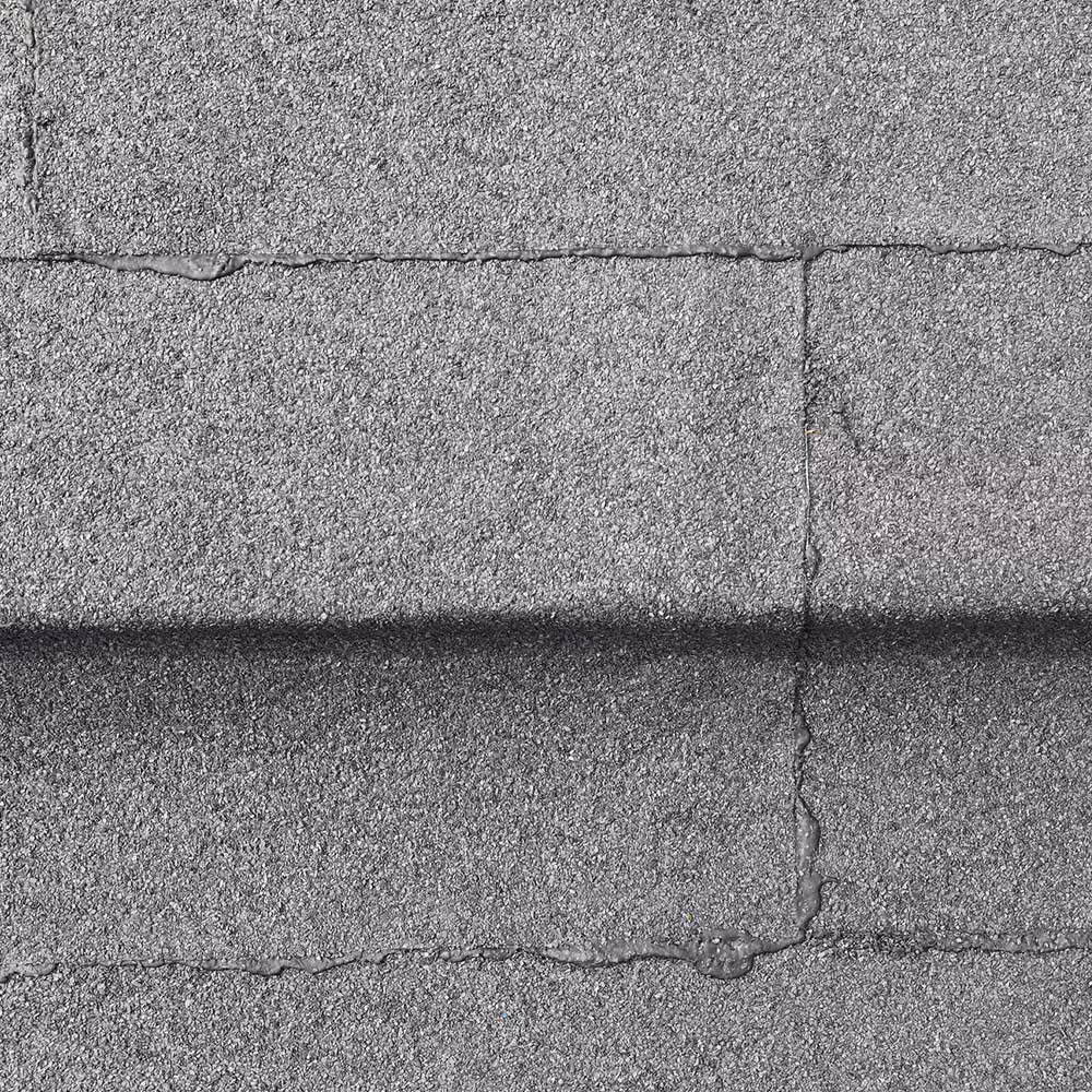 A detailed, straight-down close-up of the surface texture of the new dark grey flat roof membrane, highlighting the granular finish and the professionally sealed seams between sheets.