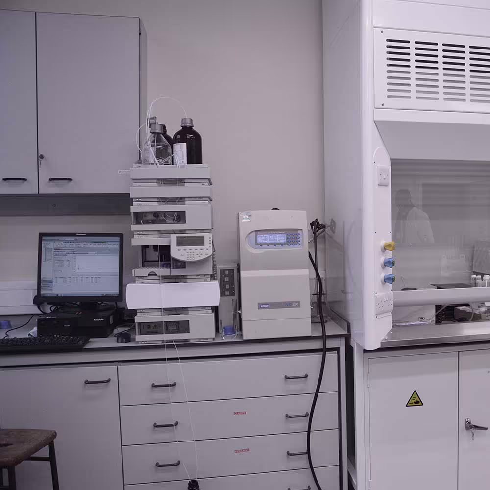 A section of the refurbished lab showing analytical equipment, including a chromatography stack and a monitor displaying scientific data, positioned next to the fume cupboard, emphasizing the high-tech capabilities of the new lab.