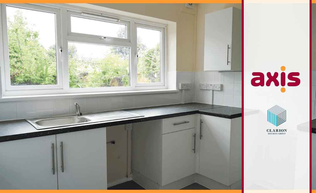 White kitchen with cupboards, sink, and window with garden. Axis logo on the right and Clarion logo on a white banner with red borders.