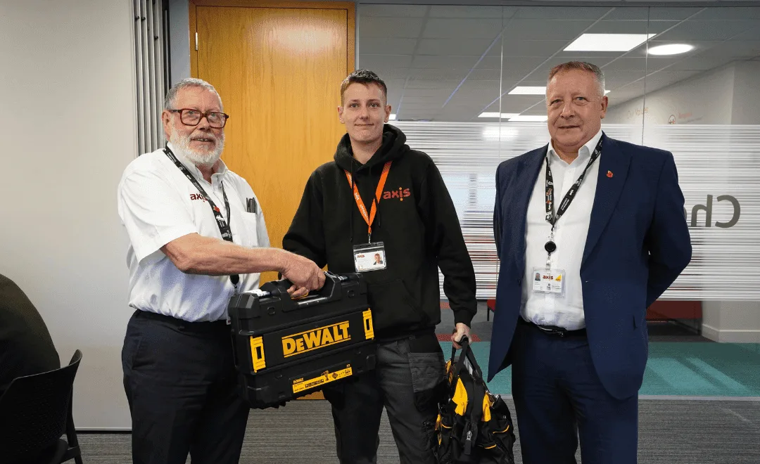 Two old man, and one young boy in the middle in an office. Suit, shirt, and black hoodie, holding a black tool kit