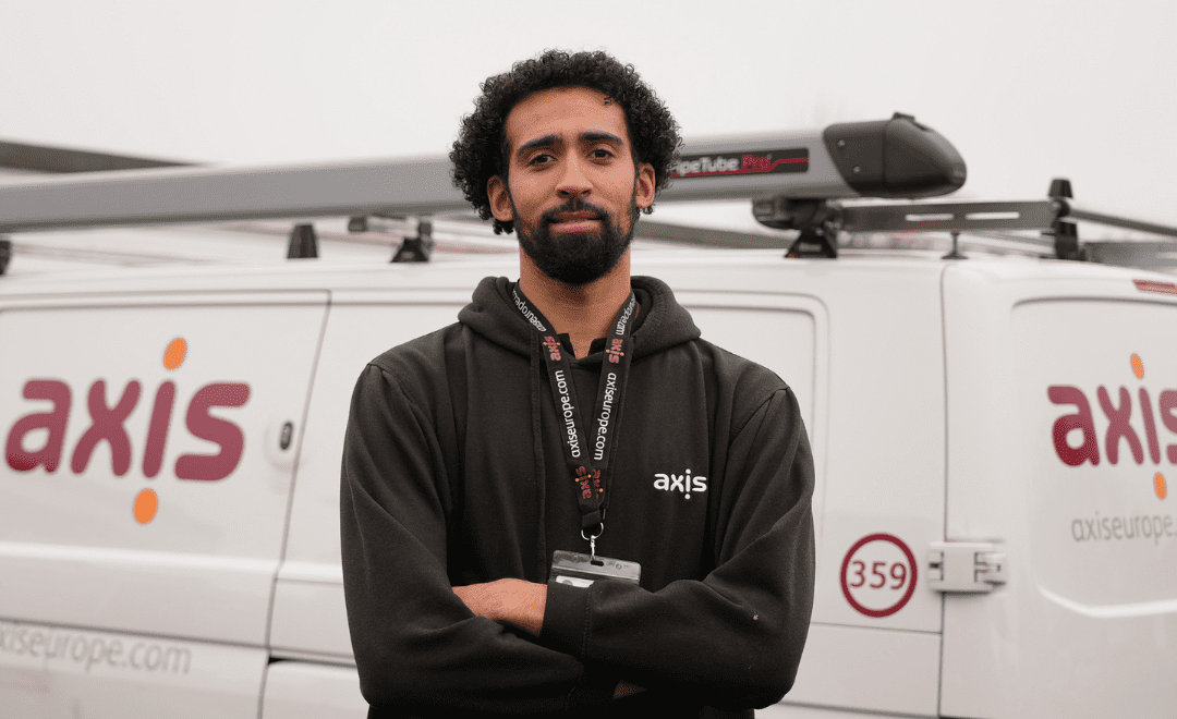 Man with black hoodie, standing in front of a white Axis Europe van.