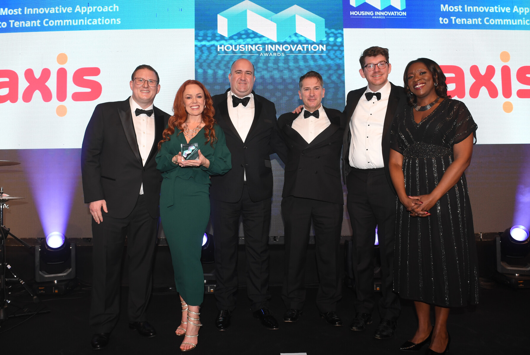 Group of people with an award. Axis logo behind.