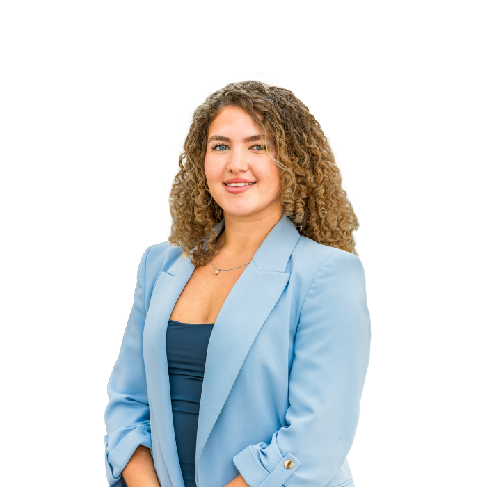 Smiling woman with curly hair with a blue blazer and top. White background behind.