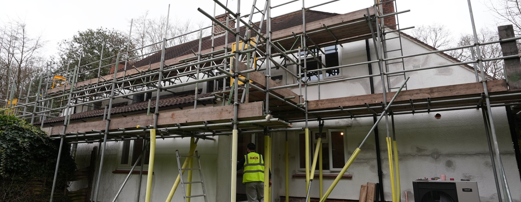 Exterior of a white lodge, scaffolding all around, outside that's white cloudy