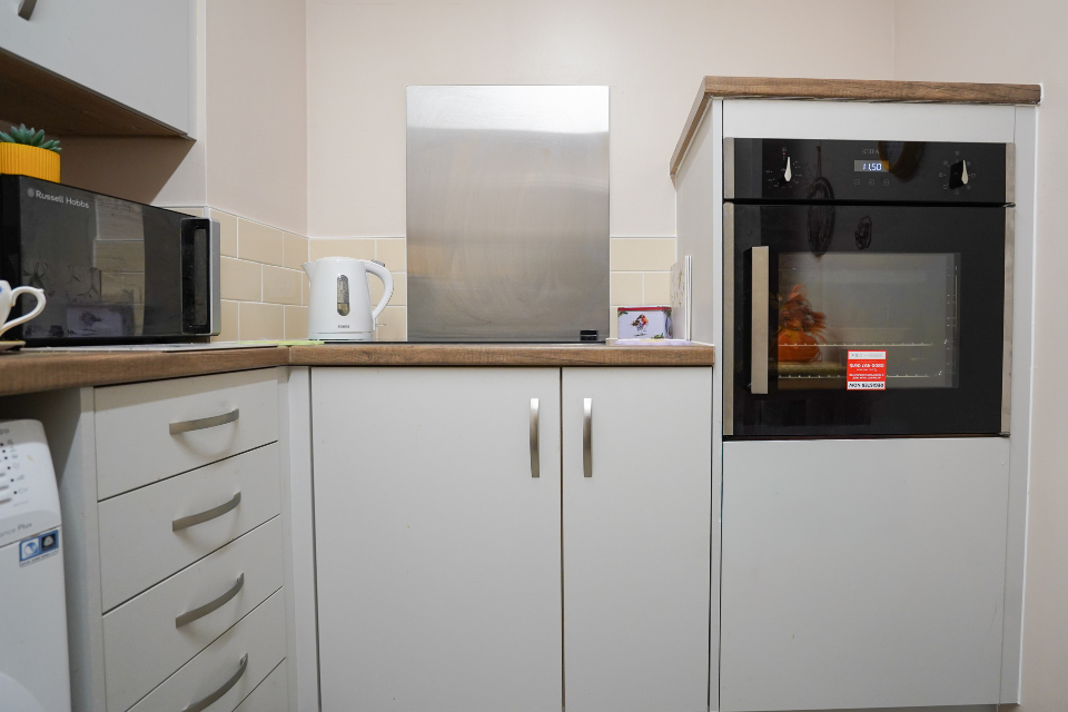 internal photo of kitchen with white units and oven