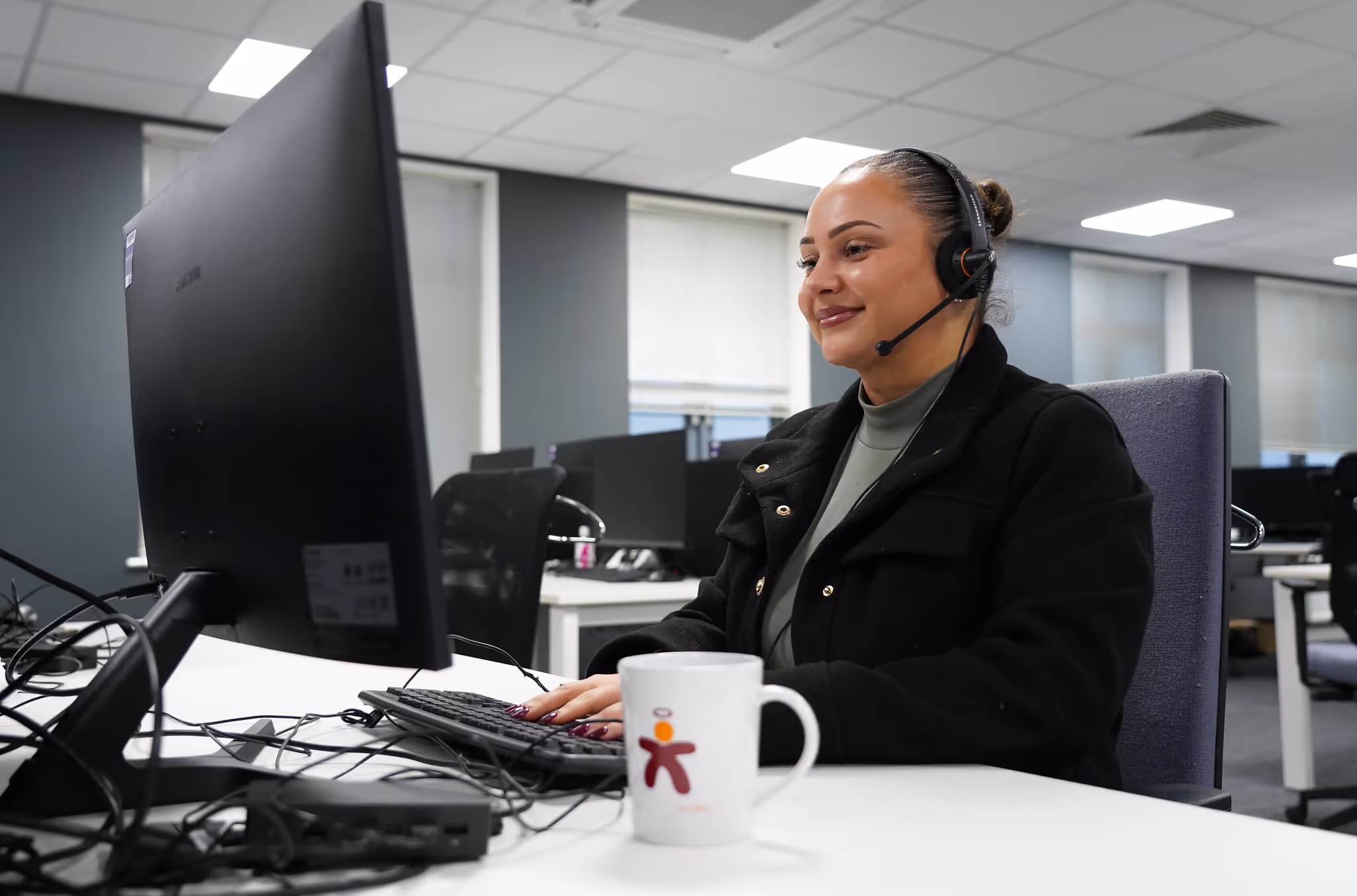 A smiling Axis employee working on a computer in the head office.
