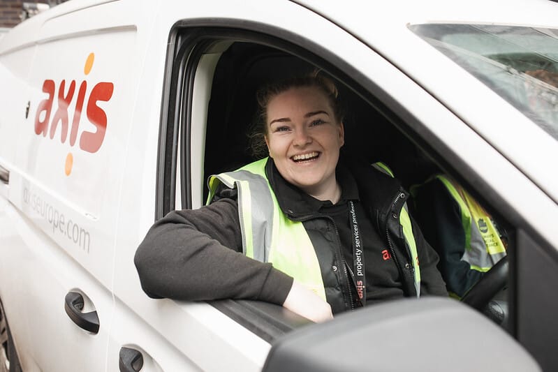 An Axis employee smiling in a branded van.