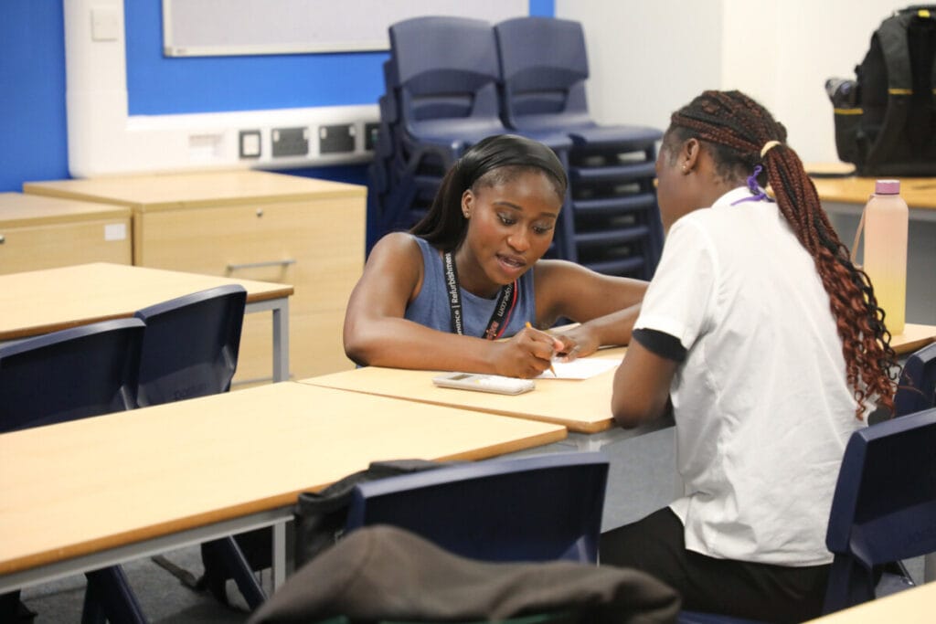 An Axis employee working with a schoolchild to help them with work inspiration.