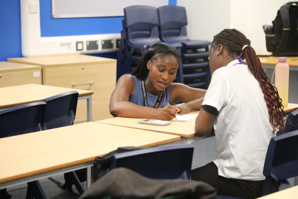 An Axis employee working with a schoolchild to help them with work inspiration.