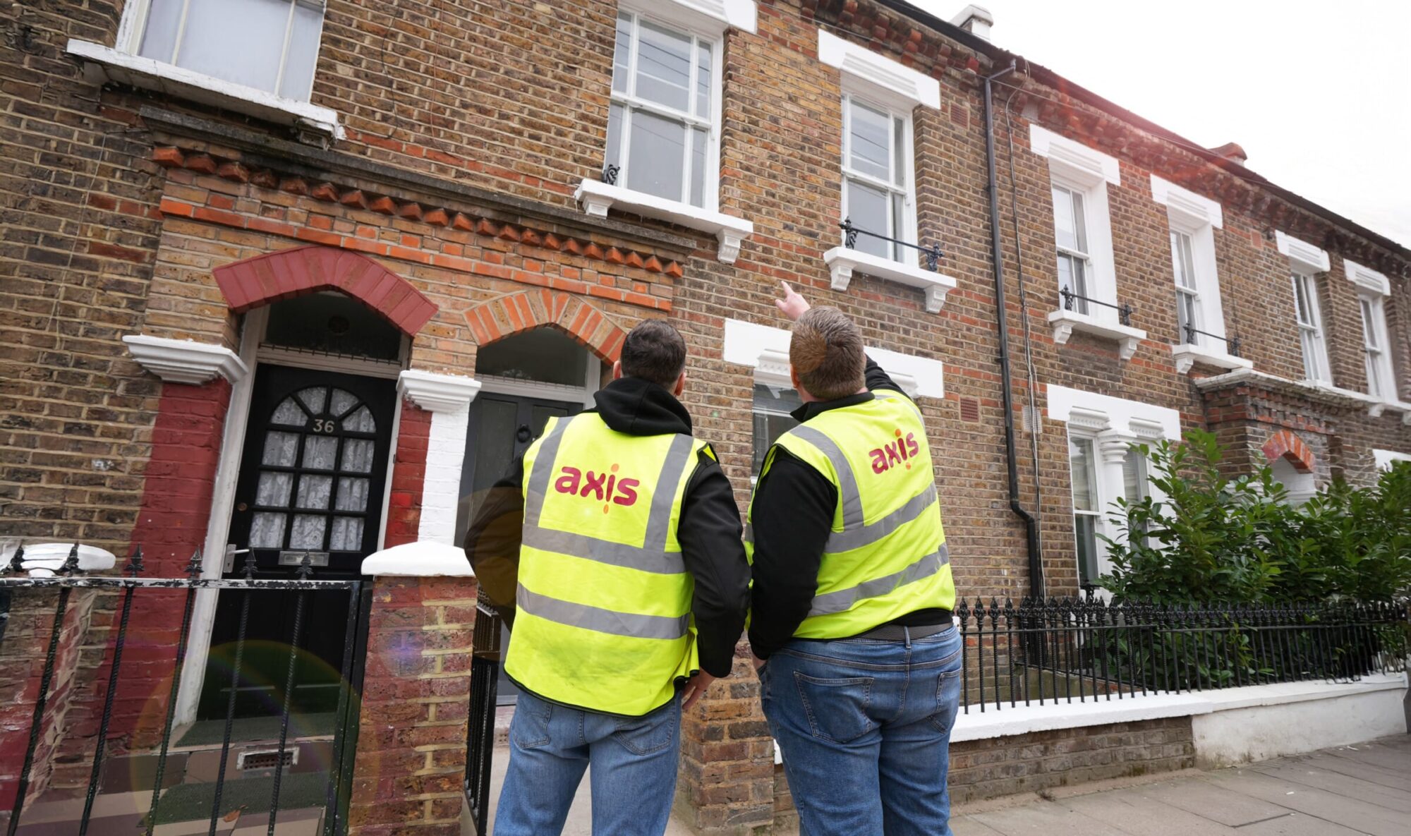 Two Axis operatives stood outside a residential property representing social housing.
