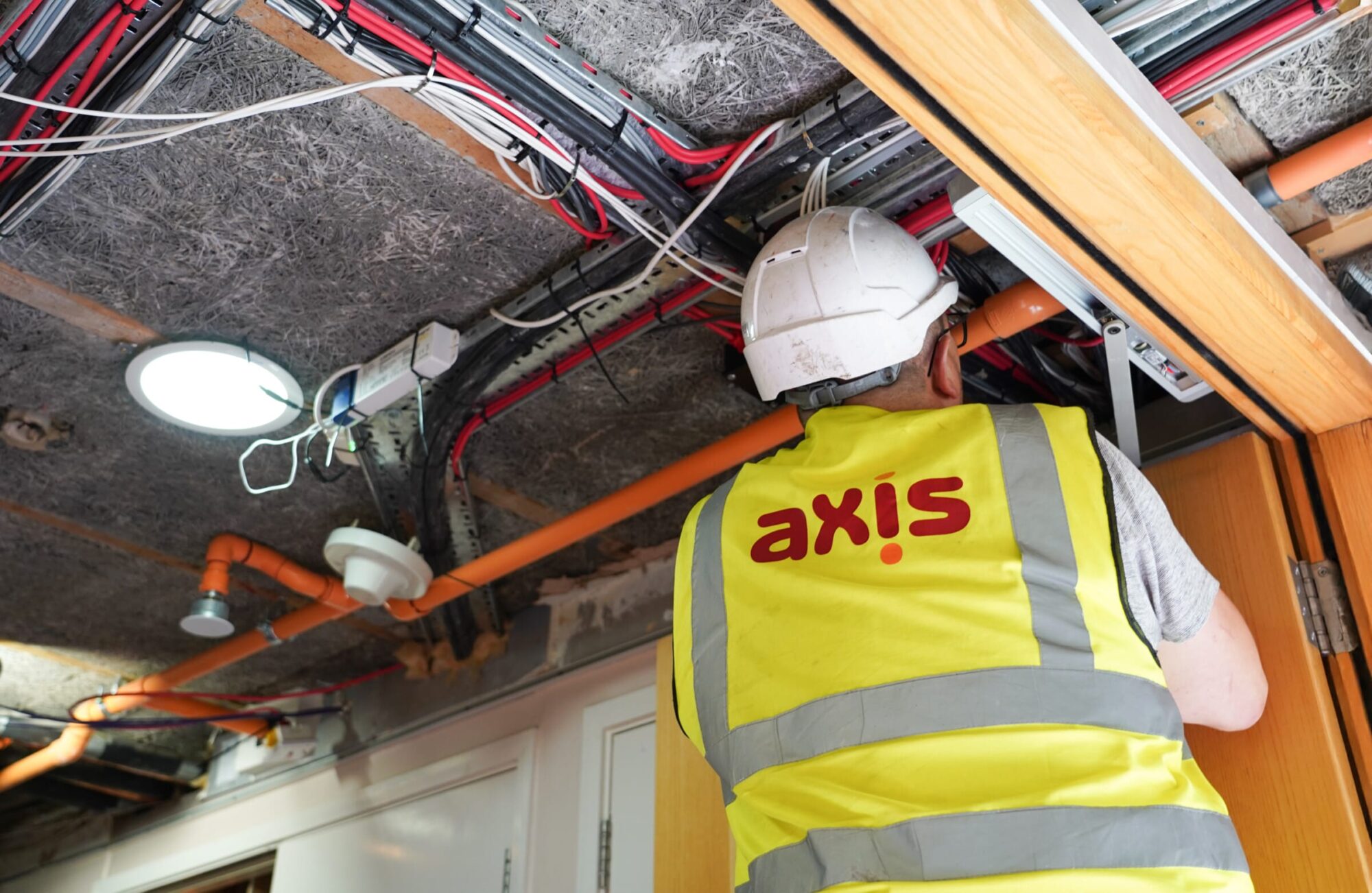 Axis employee in high-vis vests working on passive fire in ceiling.